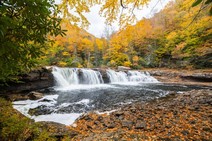 Waterfall surrounded by autumn foliage with vibrant orange and yellow leaves.