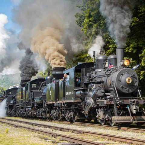 a steam engine riding on a train track with smoke coming out of it