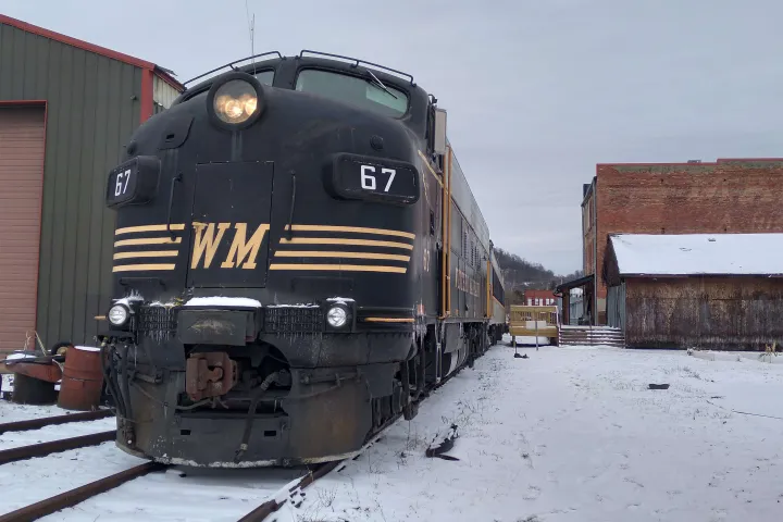 Vintage black locomotive with 'WM' and number 67, parked in a snowy rail yard.