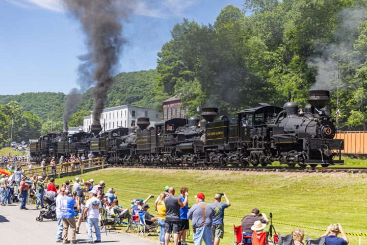 a group of people on a train track with smoke coming out of it