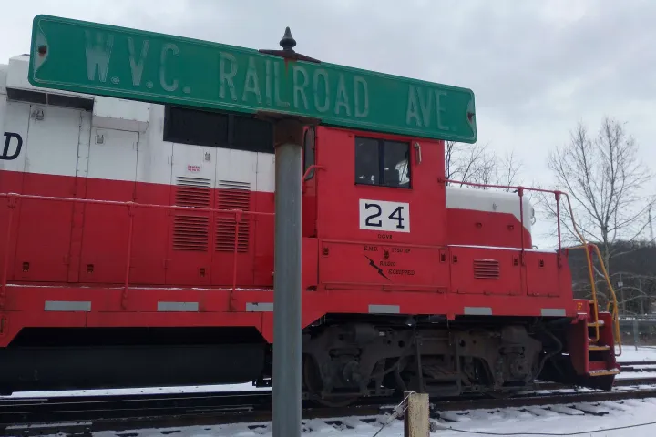 Red train engine 24 near W.V.C. Railroad Ave sign, snowy setting.