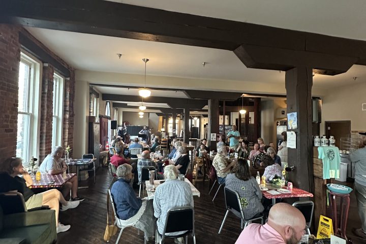 People sitting and socializing in a cozy, dimly lit room with wooden floors and brick walls.