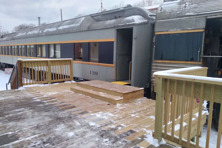 Vintage train car with snowy wooden platform and steps in winter setting.