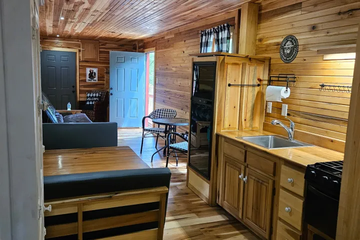 Wood-paneled cabin interior with kitchenette, sofa, and open door.