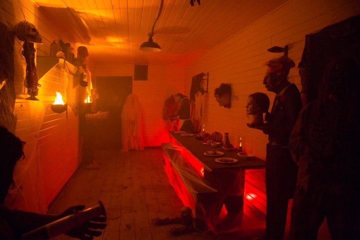 Dimly lit spooky room with Halloween decorations and eerie figures.