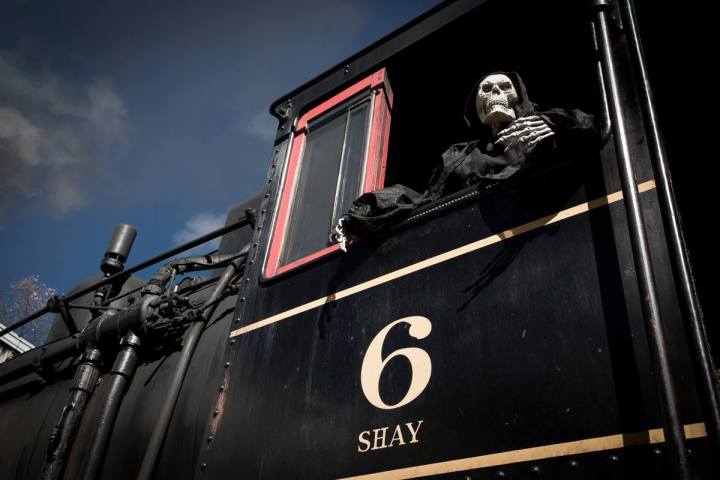 Skeleton in black robe leans out of train cabin window with number 6.