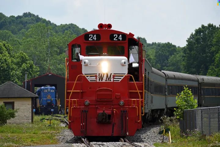 Red train engine 24 on tracks, trees in background.